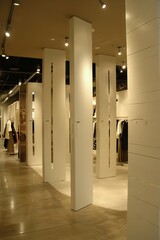 Chic women's clothing store interior, showcasing white walls contrasted with Molteni hues, partition walls, and a fusion of vintage modernism in its design.