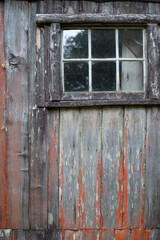 Small six paned window on the side of an old weathered building - 765999021