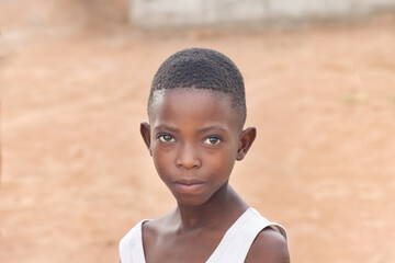 village african girl in front of her home, standing in the yard