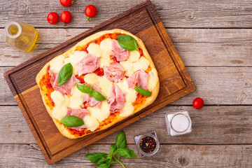 Traditional italian pizza with ham mozzarella and  basil