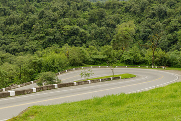 Sharp curve on a mountain route surrounded by vegetation.