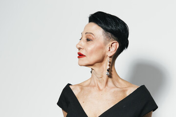 Stylish woman in black dress and red lipstick looking away from camera with elegant earrings