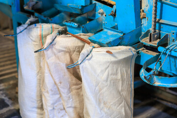 Three bags of white material are hanging from a blue machine