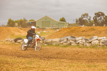 Teen boy riding motorbike at motocross track meet