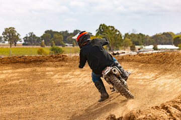 Teen boy riding motorbike at motocross track meet