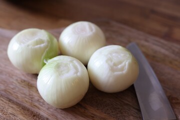 Fresh ripe onion bulbs on wooden table, closeup