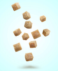 Brown cane sugar cubes falling on light blue background