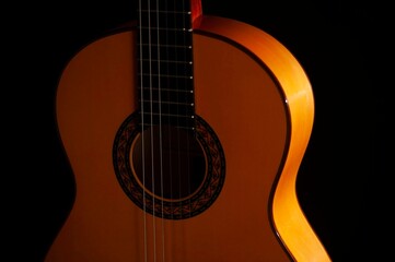 Obraz premium Classical Spanish flamenco guitar close up, dramatically lit isolated on black background with copy space.