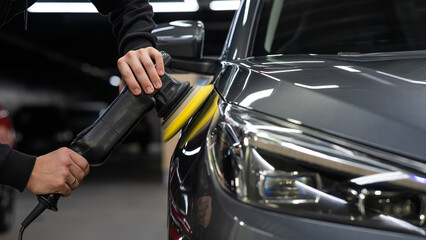 A master polishes the surface of a car body. 