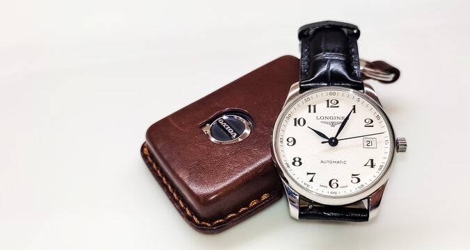 BANGKOK, THAILAND - MARCH 21 : Longines Master Collection white dial with alligator leather strap put on the white table with Volvo key fob in Bangkok, Thailand, on March 21, 2024.