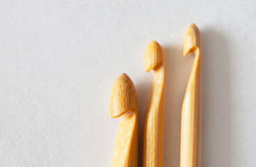 Close-up of three wooden hooks on a white background. Top view of needlework and crochet hooks made from bamboo. DIY concept. Macro, flat lay, copy space, mockup, empty place, blank