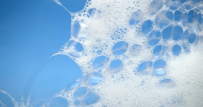 Cleaning soap bubbles popping over blue background showing cleanliness, washing, or cleaning products.