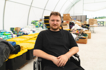 A veteran disabled man in a wheelchair helps in a humanitarian unit. Support of war victims....
