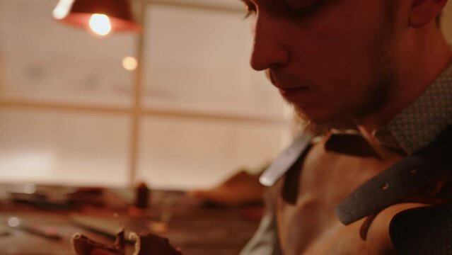 Portrait of craftsman in shoemaker workshop grinds wooden shoe last. Handmade shoemaking, handicraft industry.