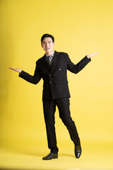 Fototapeta premium Portrait of Asian male businessman. wearing a suit and posing on a yellow background