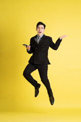 Fototapeta na wymiar Portrait of Asian male businessman. wearing a suit and posing on a yellow background