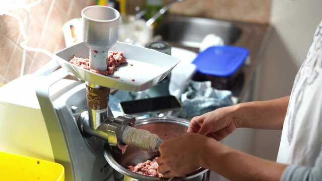 Cook puts on an intestine for stuffing sausage in a meat grinder. High quality 4k footage