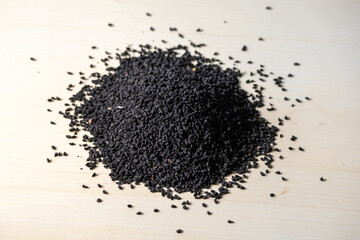 Black cumin seeds heap isolated on a wooden background. Locally in Bangladesh, it is called...