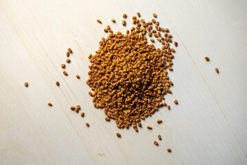 A pile of dried fenugreek seeds on a wooden surface. Locally in Bangladesh, it is called Methi. Spices for cooking and medicinal herbs, top view.  