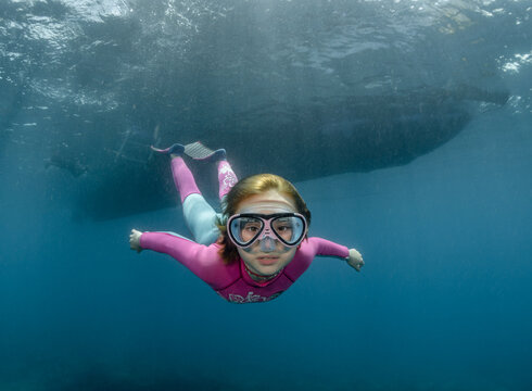 Underwater portrait of a child wearing a diving mask in the sea in the rays of the sun