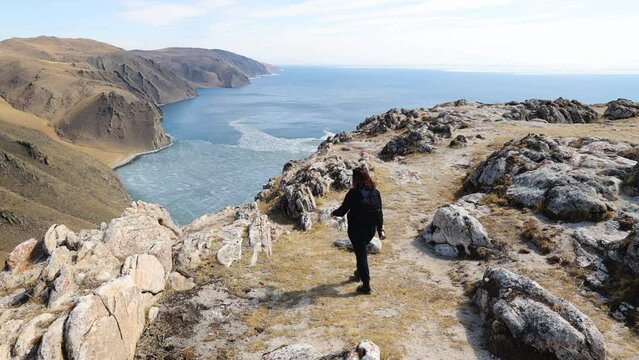 A young woman is backpacking, hiking. Beautiful view of the spring lake, mountain landscape.