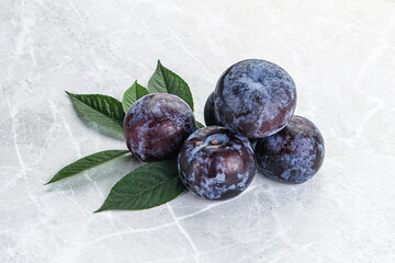 Raw purple plums heap with leaves