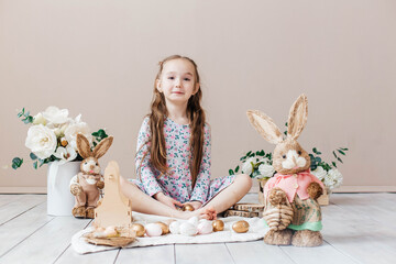 Little girl playing with Easter toy bunnies and a basket of Easter eggs. Child celebrating Easter....
