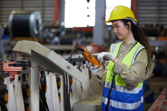 woman factory worker or engineer operating remote switch to control machine in the factory