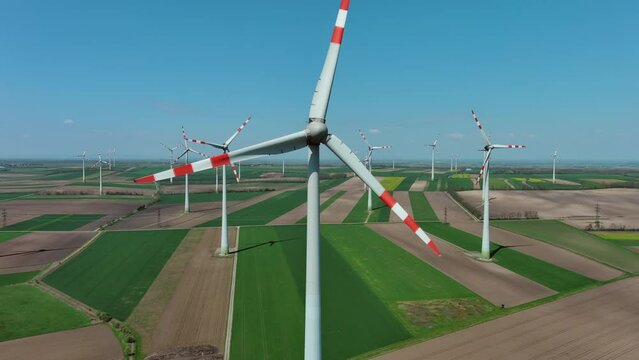 Aerial around view of wind turbines and agriculture fields. Windmills turbines generating electricity, green energy, 4k