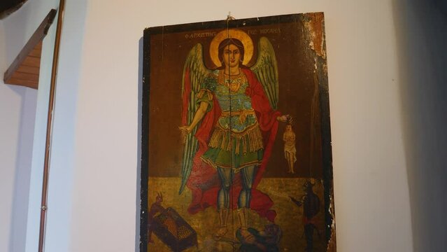 A vintage picture frame featuring a painting of St. Michael Angel hangs on the wall of the Cave of the Apocalypse in Patmos.