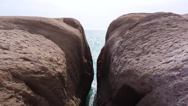 Flying over seaside rock cliff narrow slot of beach rock wonderful seascape wide view of skyline in sunset the marine adventure in Qatar nature tourist attraction Saudi border coastal mountain in Iran