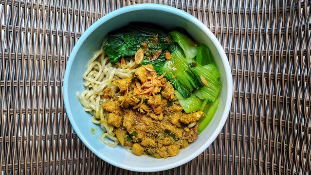 Chicken noodles with vegetables with a woven background served in a bowl