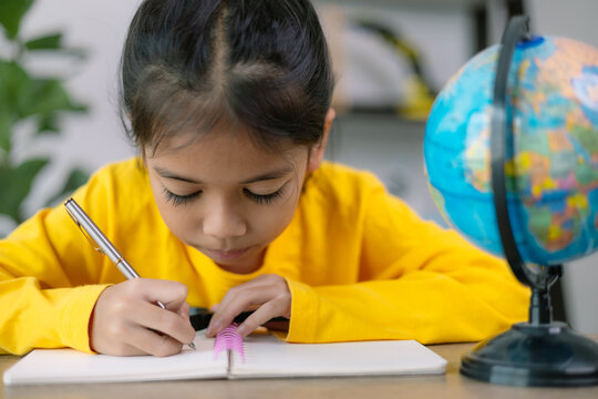 A young girl is writing in a yellow shirt