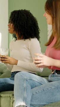 Multi-ethnic women talking and drinking at home
