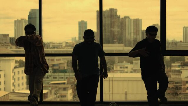 Silhouette shot of skilled choreographer group dancing together with sky scrapper, cityscape background. Young hipster team dancing performance. Yellow filter. Shadow. Outdoor sport 2024. hiphop.