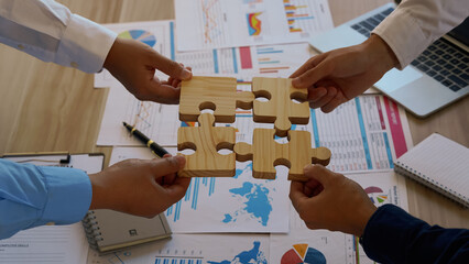 Four hands trying to connect couple puzzle piece with sunset background. Jigsaw alone wooden puzzle...