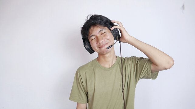 Asian man gesturing excitedly happy using earphones on white background