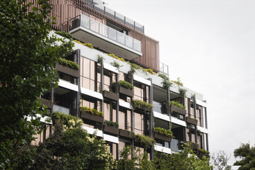 Clean, green energy urban building covered in plants and fauna. Ecological living in the city.