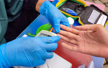 Blood tests on fingertip for uric acid, hemoglobin, sugar and cholesterol levels using a lancing device for muslim woman patients