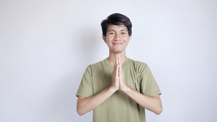 Close-up of handsome Asian man smiling with greeting gesture - obrazy, fototapety, plakaty