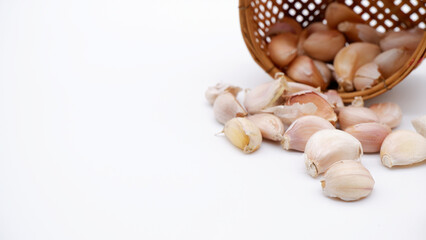 Garlic and blurred small woven basket on the back. Fresh garlic on white background with the concept of rustic kitchen, home cooking, vegetables, ingredient, herbs and spices. Close-up organic garlic.