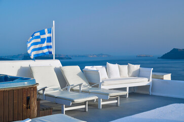 santorini oia city grreece view to the sea greek flag waving  - obrazy, fototapety, plakaty