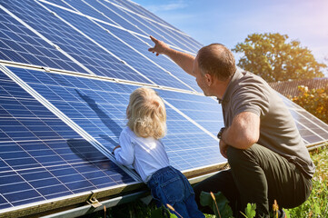 Man showing his son solar panels during sunny day. Father presentng to child modern energy...