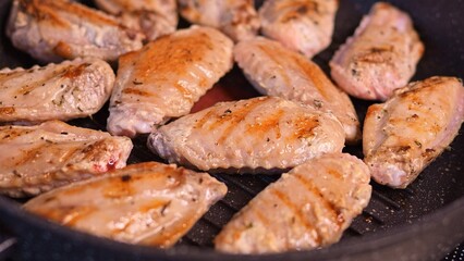 Fried fast-food chicken wings on skillet. Observe how fried wings elevate cholesterol levels. Delve into the effects of cholesterol as fast-food sizzles, stimulating the sense. Cholesterol is harmful