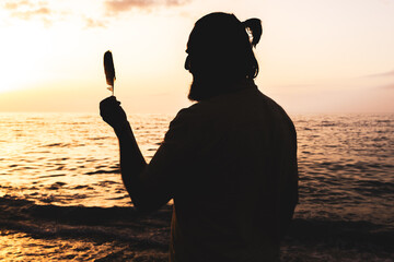 A man is standing on the beach holding a feather