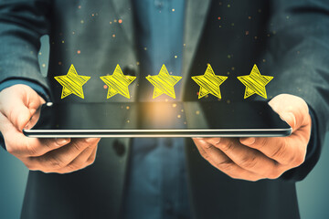 Close up of businessman hand holding tablet with 5 star rating on blurry background. Customer...