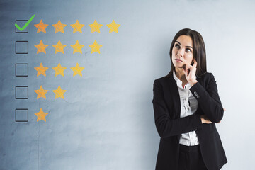 Thoughtful young businesswoman with 5 star rating on concrete wall background. Customer service and...