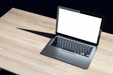 Top view of dark designer office workplace with white mock up laptop on wooden desk. 3D Rendering.