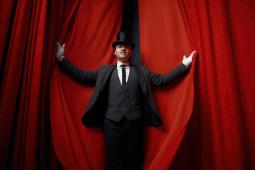 Cinematic posed portrait of magician actor over red velvet stage curtain