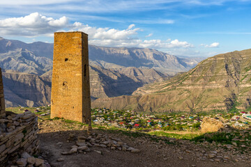 Stone tower and old ruined aul against amazing landscape with mountains and village. Ancient caucasian village Goor, Dagestan republic, Russia, Caucasus. Famous place, popular landmark